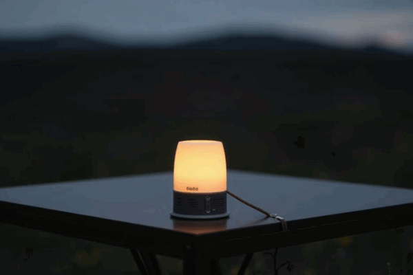 BioLite BaseLantern M glowing softly on a camping table in the evening